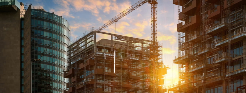 Construction site with tower crane and scaffolding at sunset, builders specifying building materials